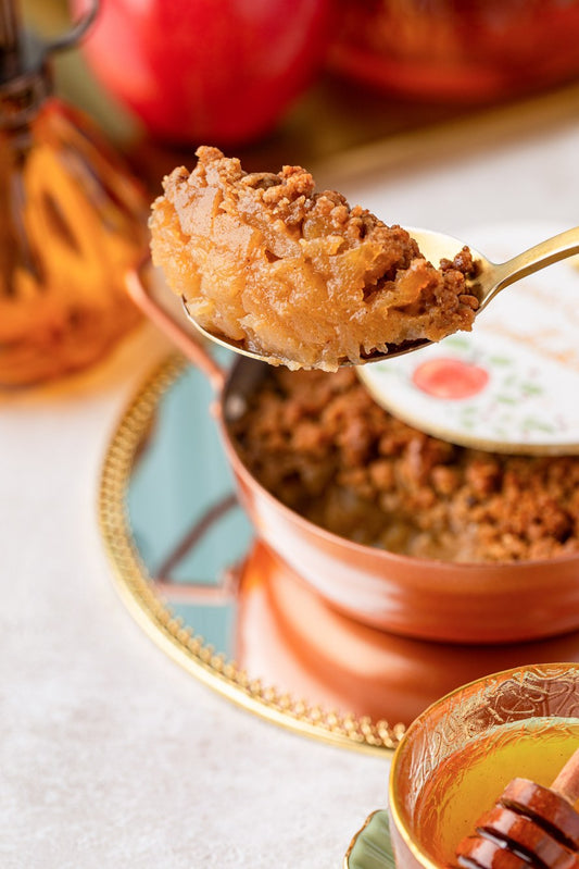 Colherada de crumble de maçã saindo da panelinha de cobre