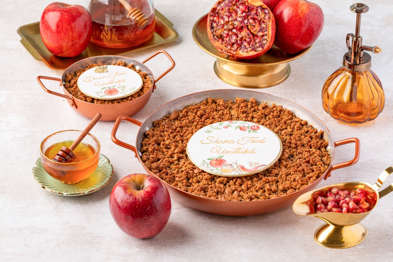 Panelinha de cobre com crumble de maçã e a plaquinha Shaná Tová Umetuká na mesa posta